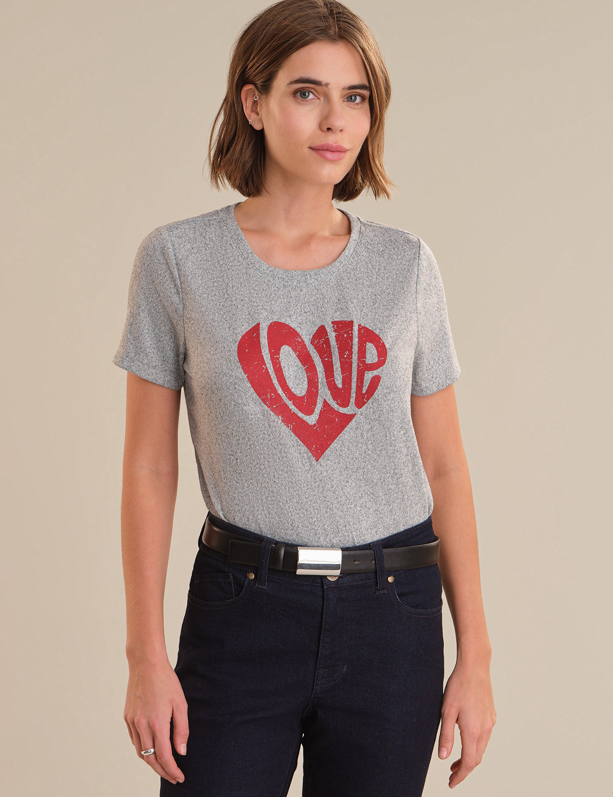 Woman wearing a gray t-shirt with a red heart and 'LOVE' print on a beige background