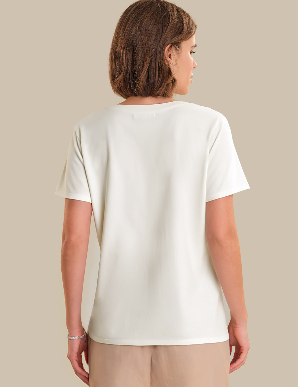 Person wearing a plain white t-shirt against a beige background