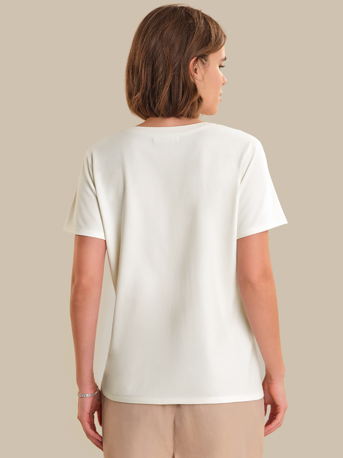Person wearing a plain white t-shirt against a beige background
