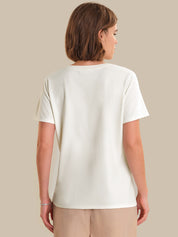Person wearing a plain white t-shirt against a beige background