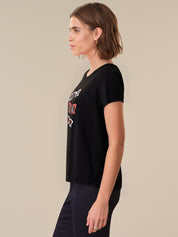 Woman wearing a black t-shirt with a graphic design on a beige background