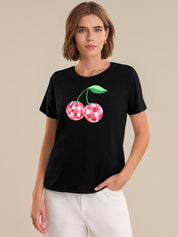 Woman wearing a black t-shirt with a cherry design on a beige background