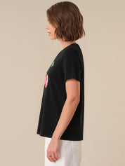 Person wearing a black t-shirt with a colorful graphic on a beige background