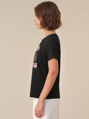 Person wearing a black t-shirt with a graphic design on a plain background