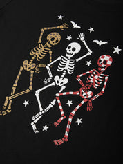 A close-up of a black garment featuring a graphic print of three dancing skeletons in gold, white, and red-and-white checkered patterns, surrounded by white stars and small bats.