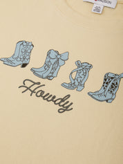 Beige t-shirt with blue cowboy boot designs and 'Howdy' text on a plain background