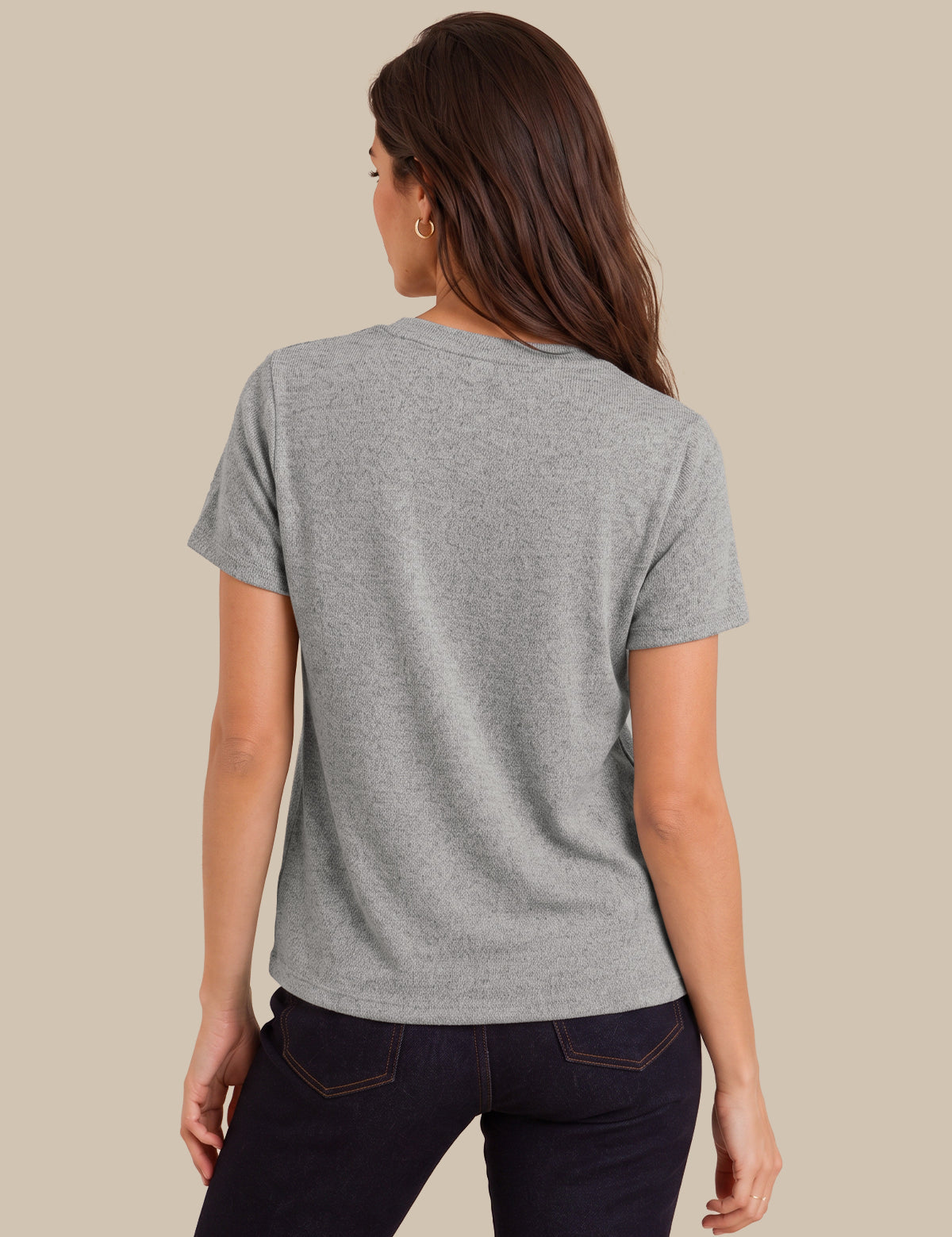 A woman shown from the back wearing a heather gray short-sleeve t-shirt and dark jeans, set against a solid beige background.
