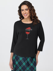 Woman wearing a black long-sleeve shirt with a wine glass design on a white background