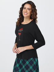 Woman wearing a black sweater with a red wine glass design on a white background