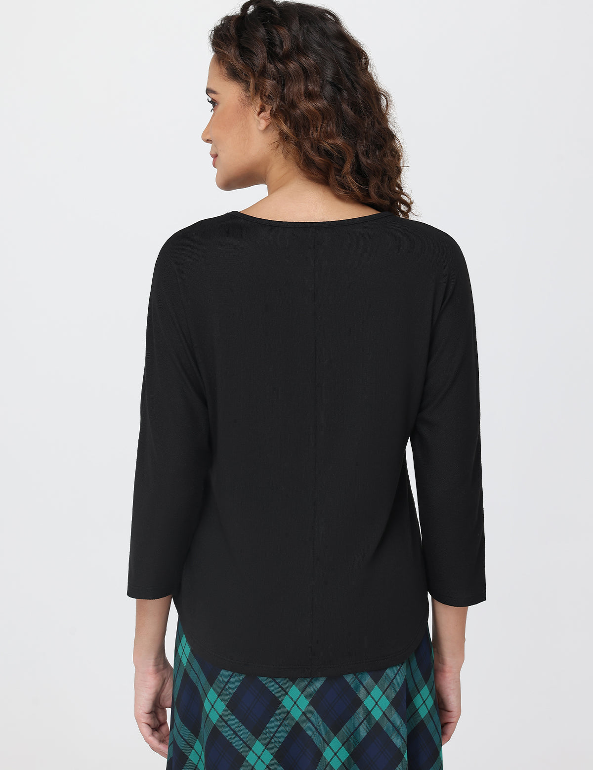 Woman wearing a black top with a plaid skirt on a white background