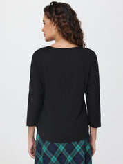 Woman wearing a black top with a plaid skirt on a white background