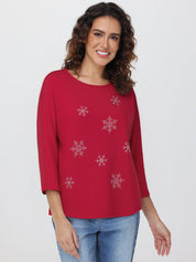 Woman wearing a red top with snowflake patterns on a white background