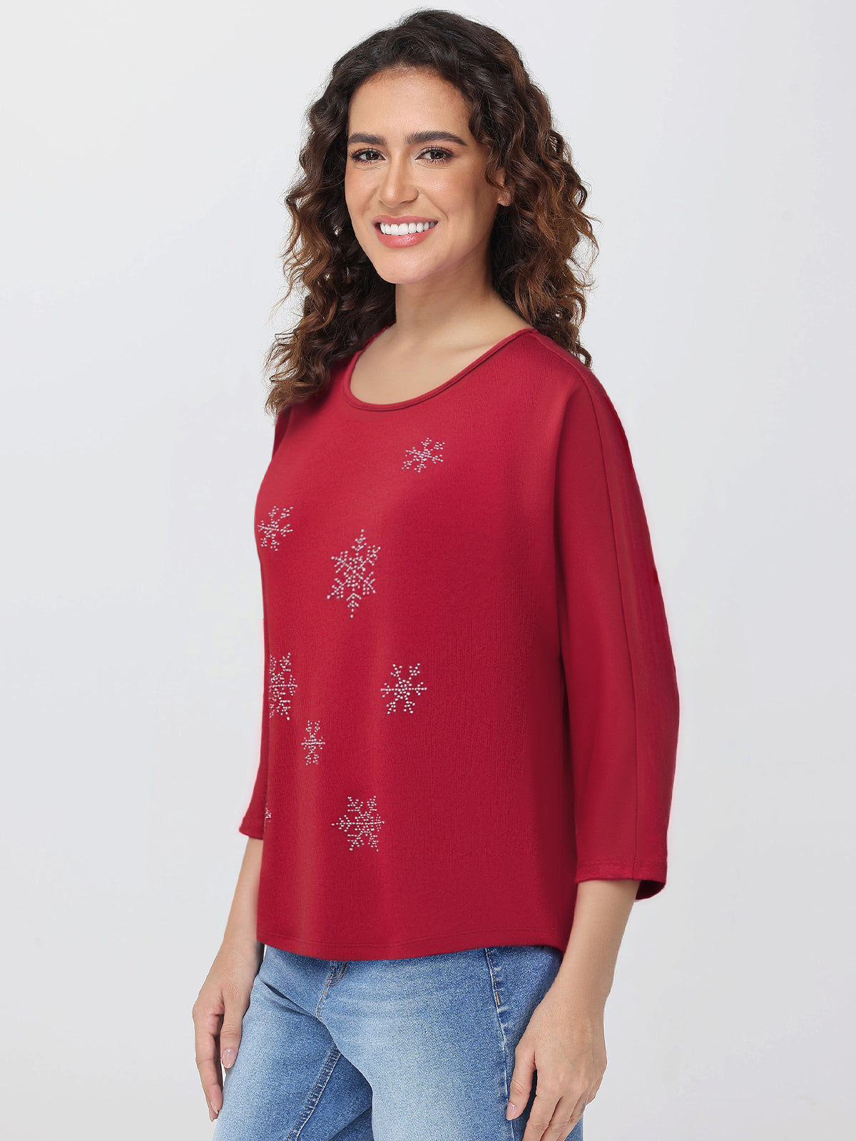 Woman wearing a red blouse with snowflake patterns on a plain background