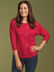 Woman wearing a red top with floral patterns on a green background