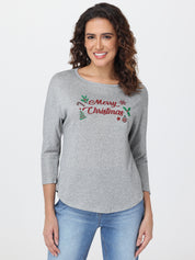 Woman wearing a gray top with 'Merry Christmas' text and festive design on a plain background
