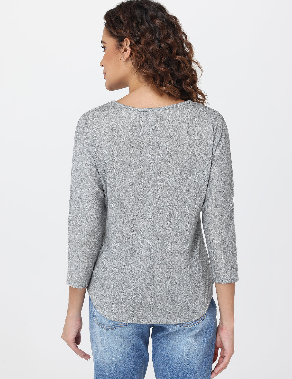 Woman wearing a gray top and blue jeans on a white background