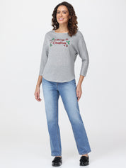 Woman wearing a gray top with Christmas text and blue jeans on a white background