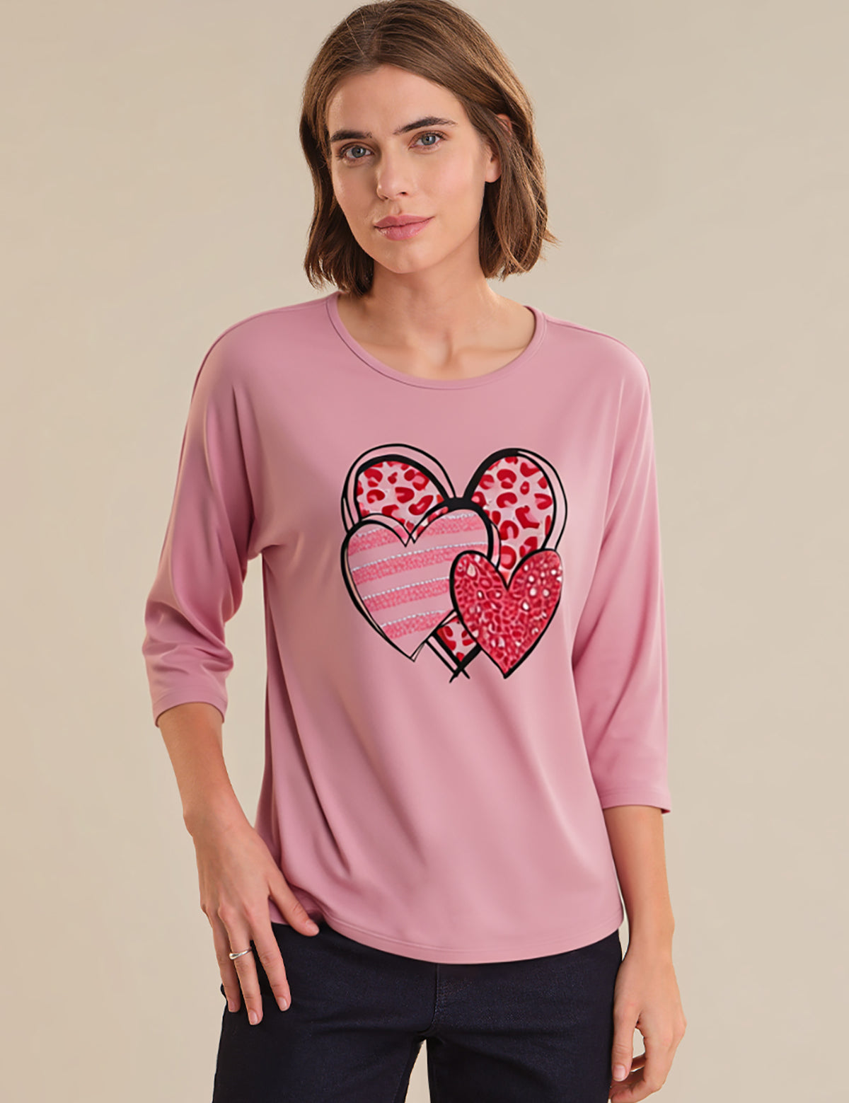 Woman wearing a pink long-sleeve top with heart designs on a beige background