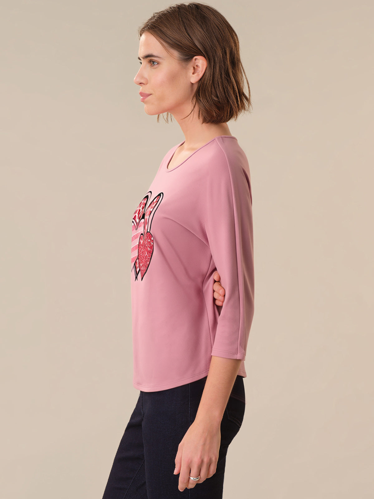 Woman wearing a pink shirt with a graphic design on a beige background