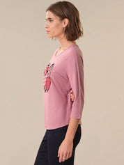 Woman wearing a pink shirt with a graphic design on a beige background