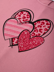 Pink sweatshirt with heart designs featuring leopard print and stripes on a pink background