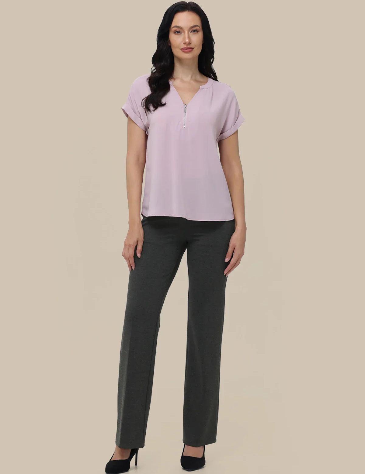 Woman wearing a light purple blouse and dark gray pants on a beige background