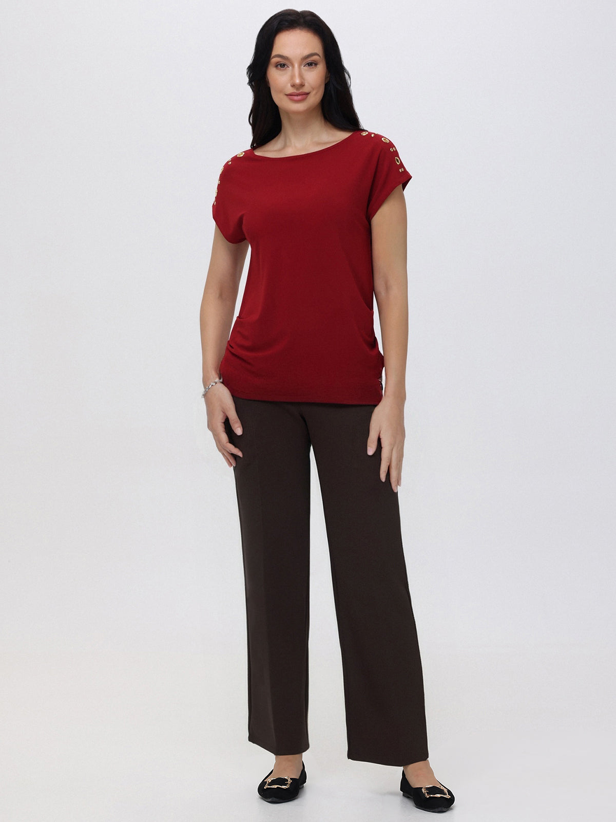 Woman wearing a red top and brown pants on a white background