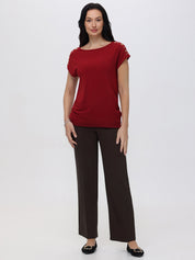 Woman wearing a red top and brown pants on a white background