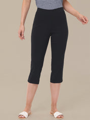 Person wearing black capri pants on a beige background