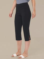 Person wearing black capri pants with a beige background