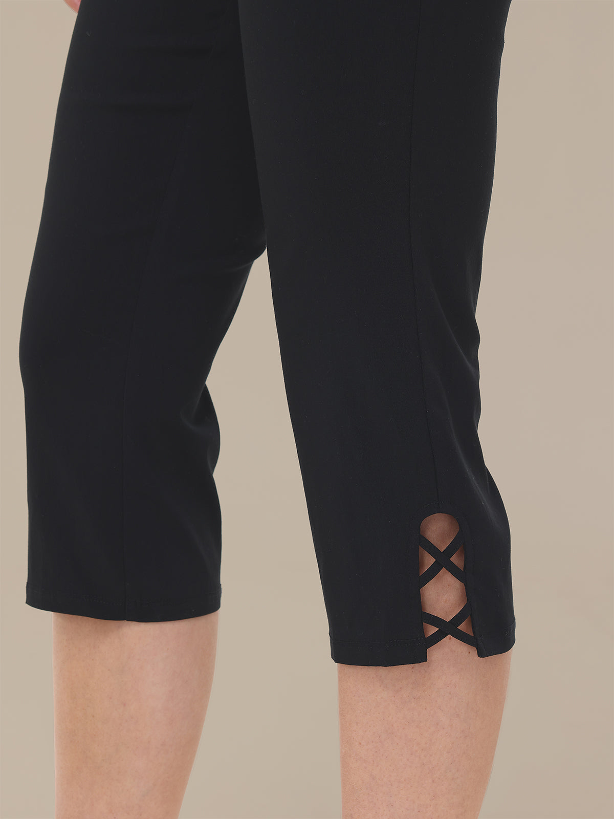 Black capri pants with lace-up side detail on a beige background
