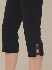 Black capri pants with lace-up side detail on a beige background