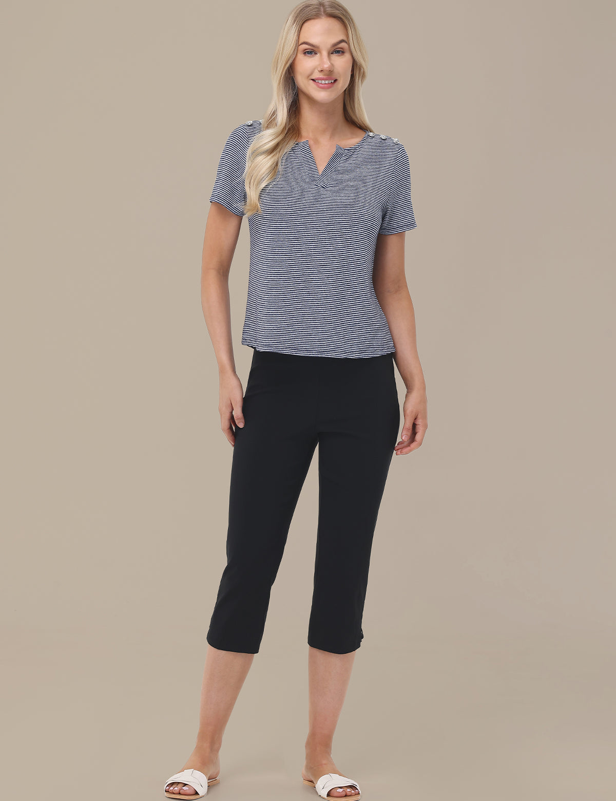 Woman wearing a blue top and black capri pants on a beige background