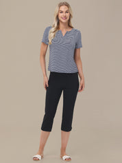 Woman wearing a blue top and black capri pants on a beige background