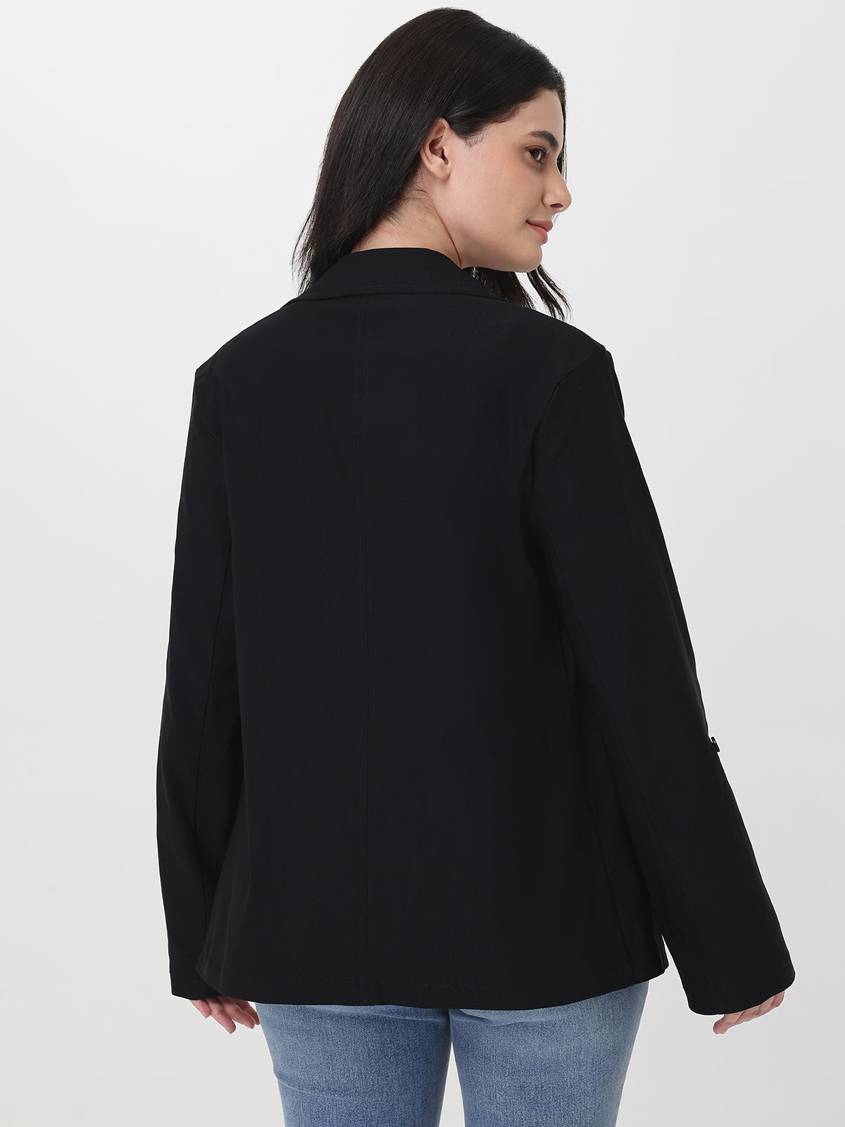 Person wearing a black blazer and blue jeans on a white background