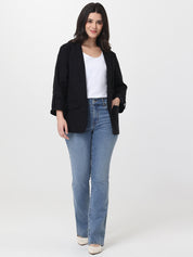 Woman wearing a black blazer, white top, and blue jeans on a white background