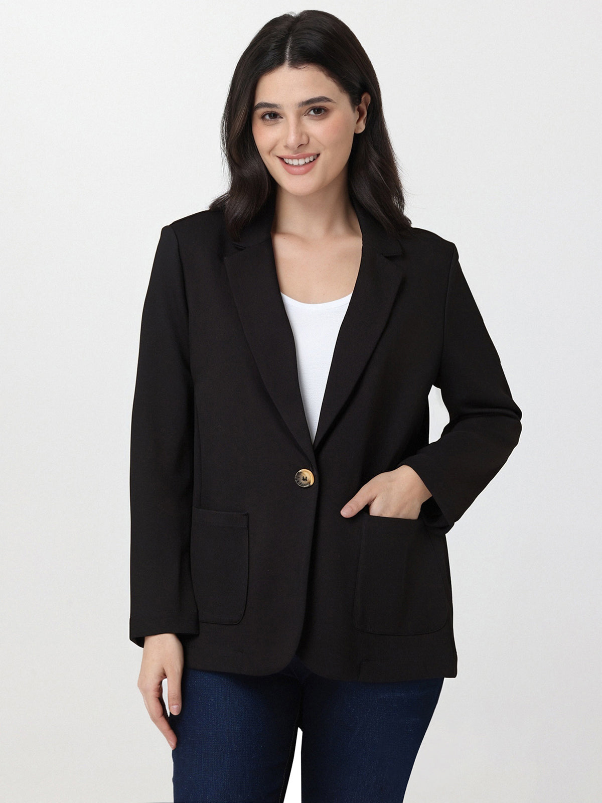 Woman wearing a black blazer over a white top on a light gray background