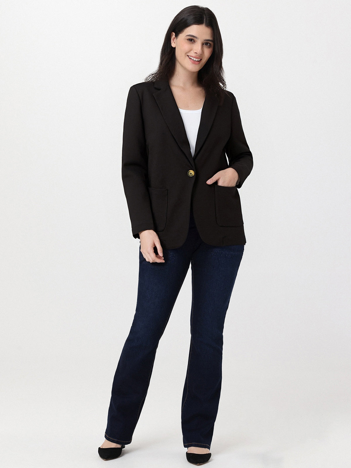 Woman wearing a black blazer and blue jeans on a white background
