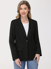 Woman wearing a black blazer over a white shirt and blue jeans on a light gray background