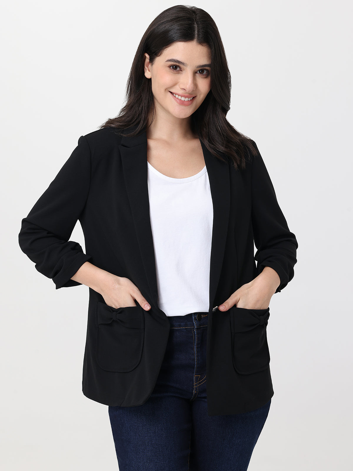 Woman wearing a black blazer over a white shirt on a plain background