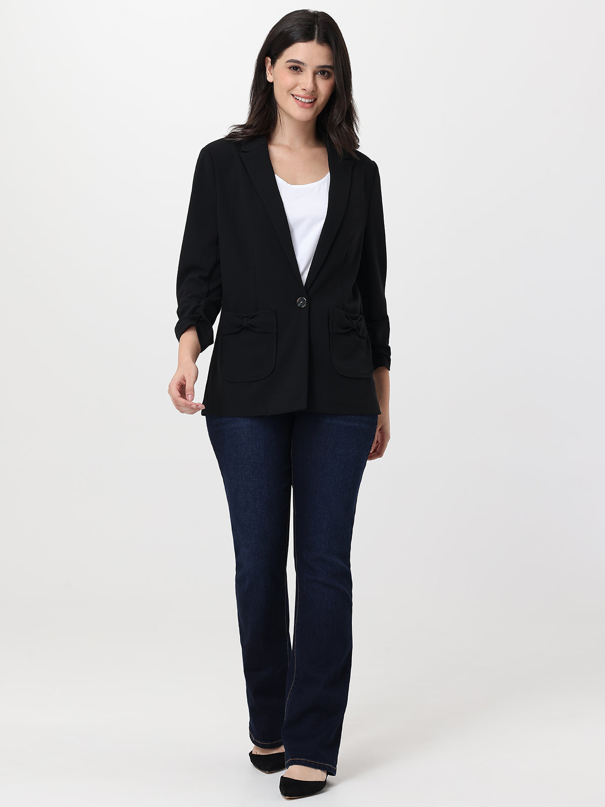 Woman wearing a black blazer and blue jeans on a white background