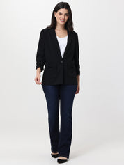 Woman wearing a black blazer and blue jeans on a white background