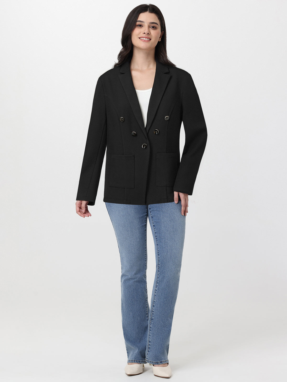 Woman wearing a black blazer and blue jeans on a white background
