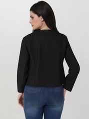 Woman wearing a black jacket and blue jeans on a plain background