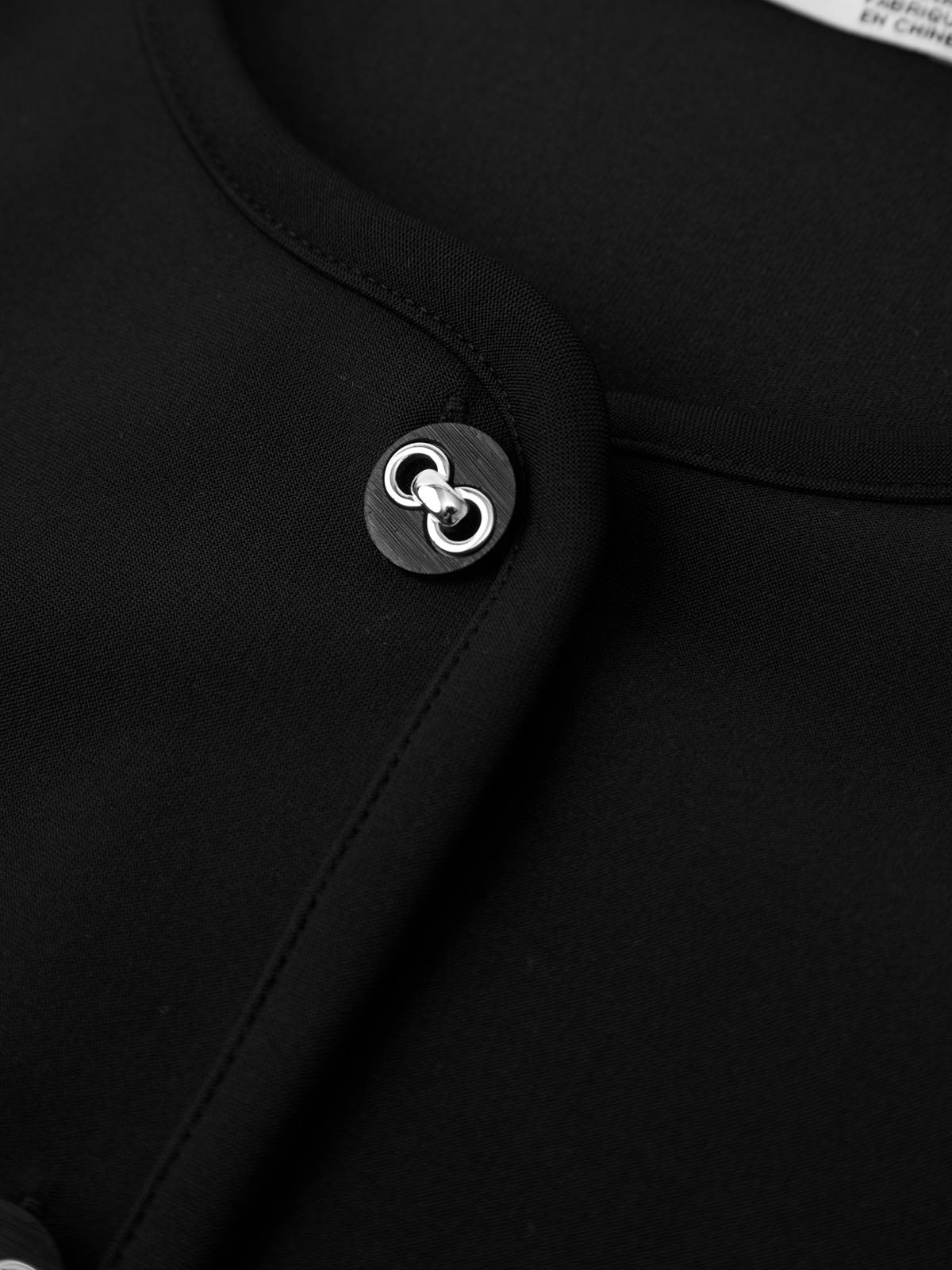 Close-up of a black garment with a button featuring a logo.