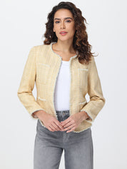 Woman wearing a beige tweed jacket over a white top and gray jeans on a light gray background