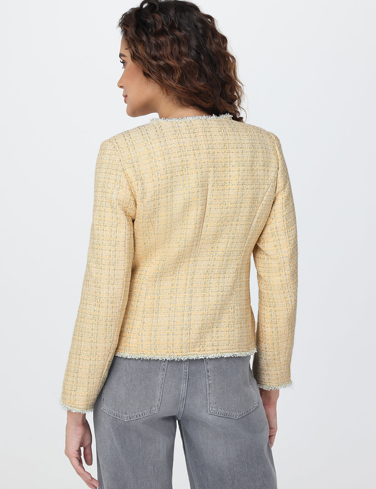 Woman wearing a light yellow checkered jacket and gray pants on a white background