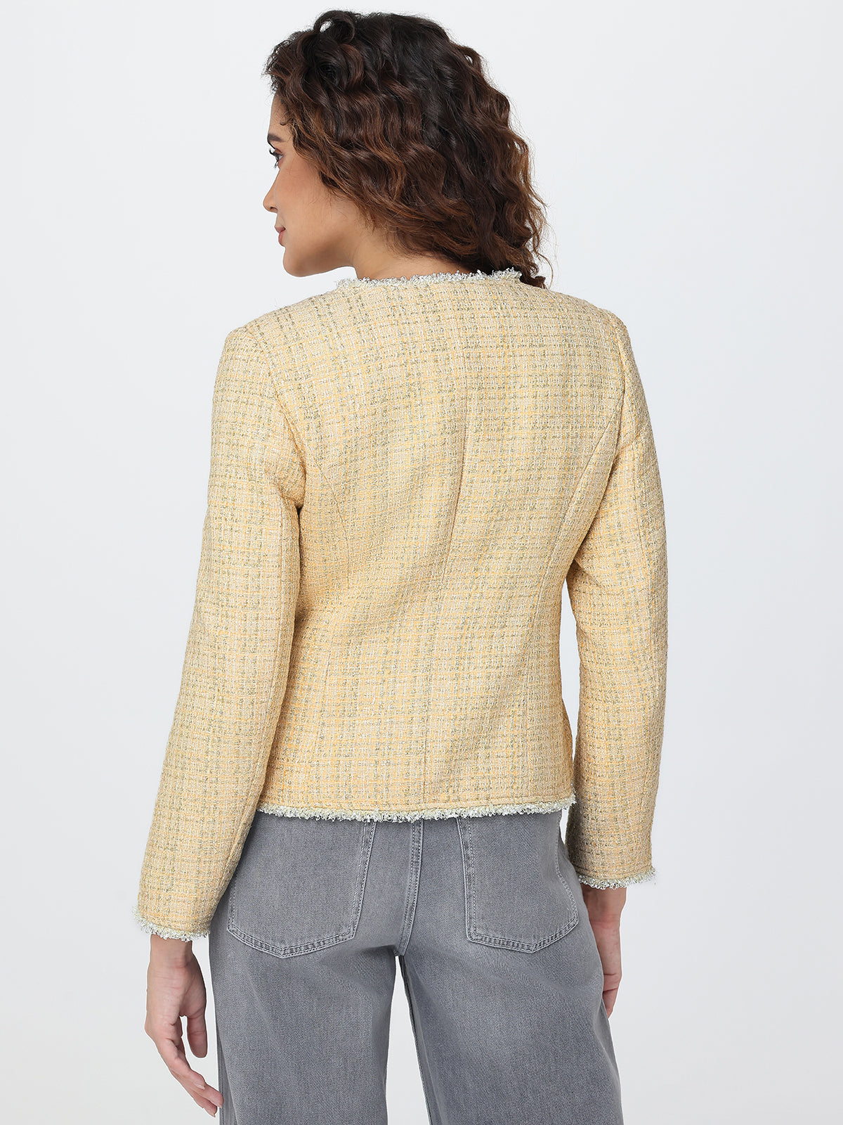 Woman wearing a light yellow checkered jacket and gray pants on a white background