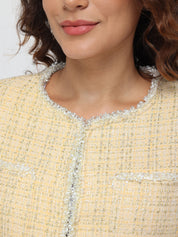 Close-up of a person wearing a yellow textured garment with silver trim.