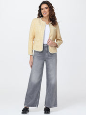 Woman wearing a light yellow jacket and gray wide-leg jeans on a white background